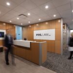 Pihl Law Office Reception with Employees Walking and Pihl Law logo on wooden background wall