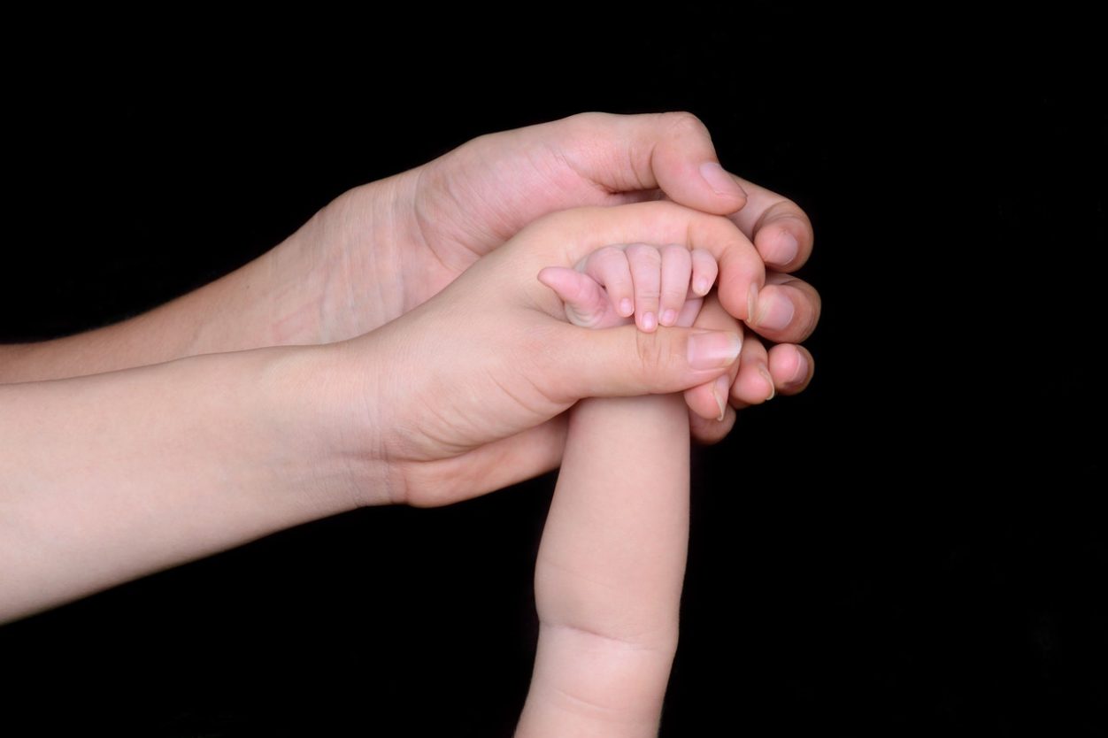 A child's hand being held by a mother and a father's hand