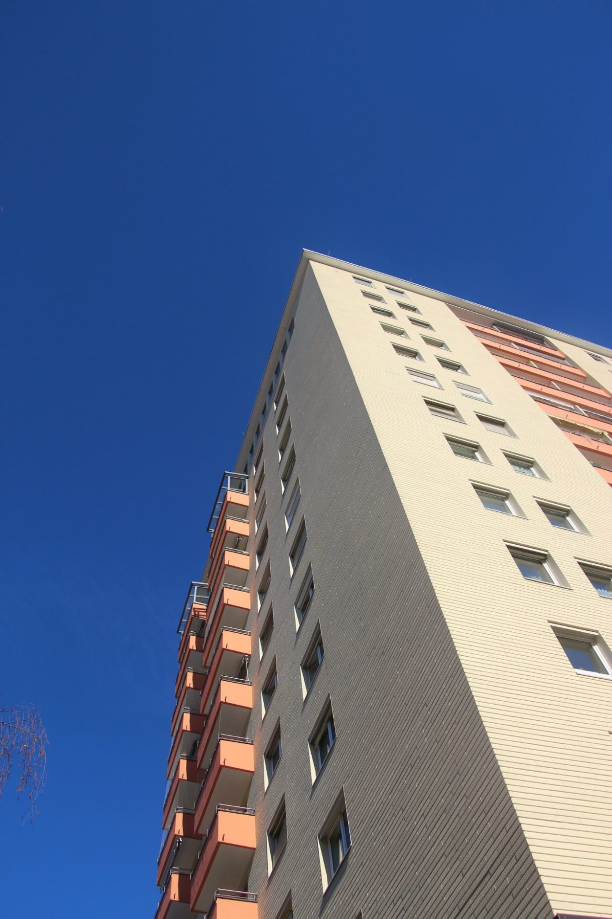 tall apartment building looking up from below, against a clear blue sky