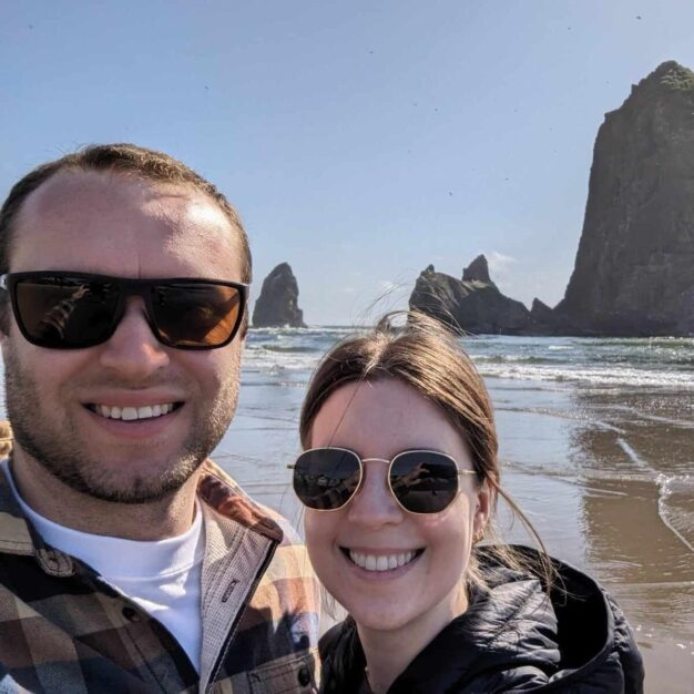 Photo of Connor Elliott in sunglasses with his wife on a beach in the Pacific Northwest.