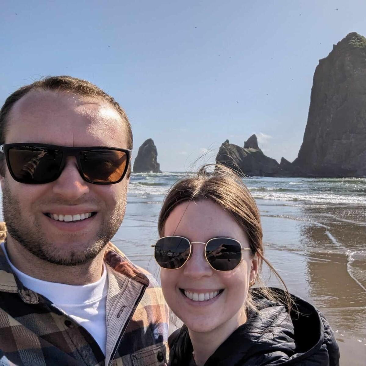 Photo of Connor Elliott in sunglasses with his wife on a beach in the Pacific Northwest.