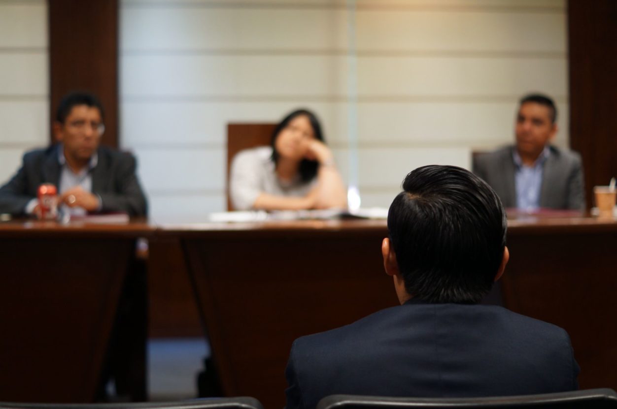 a closeup view of a lawyer's head from behind, looking at a panel of judges