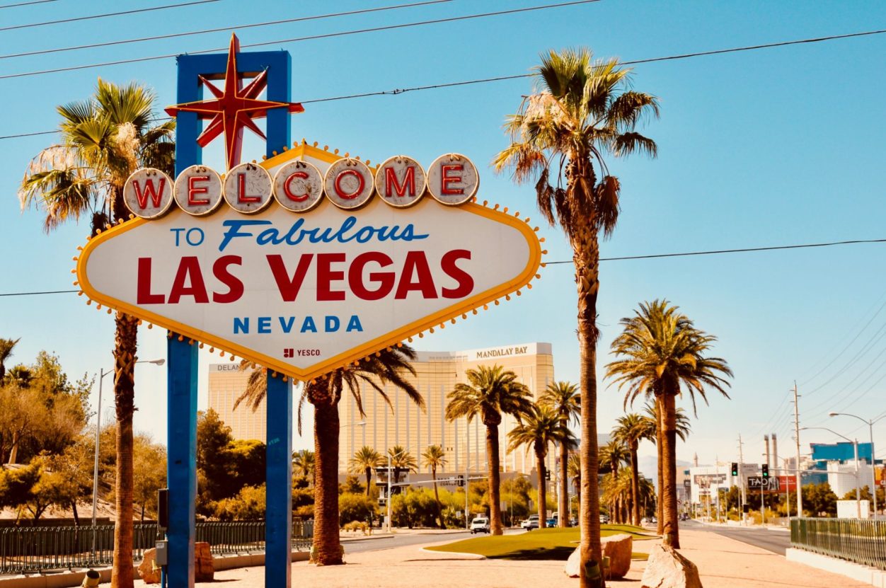 the welcome to las vegas sign in front of Mandalay Bay hotel with palm trees surrounding