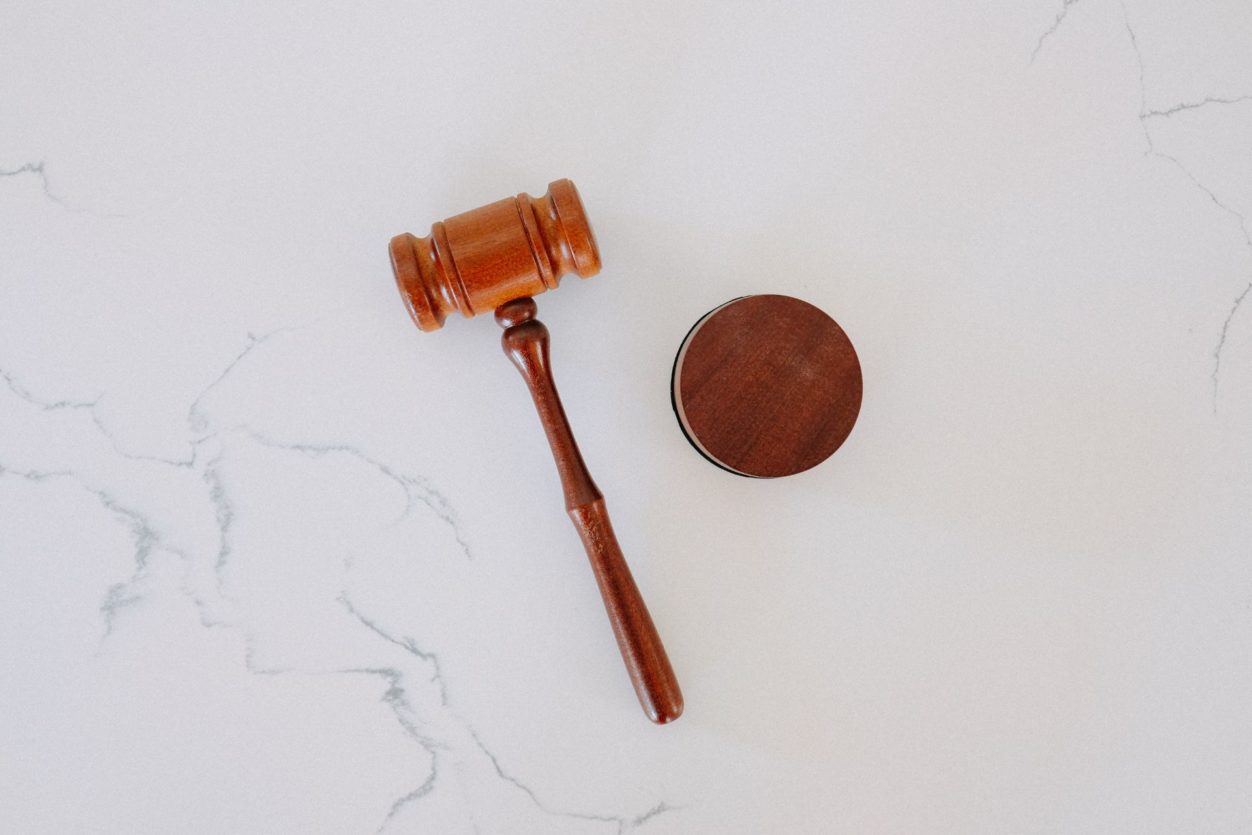 a judges wooden gavel used in a court of law, sitting on a white marble surface