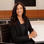 Remy Ventura professional headshot. She's sitting at a table in Pihl Law offices in Kelowna, BC.