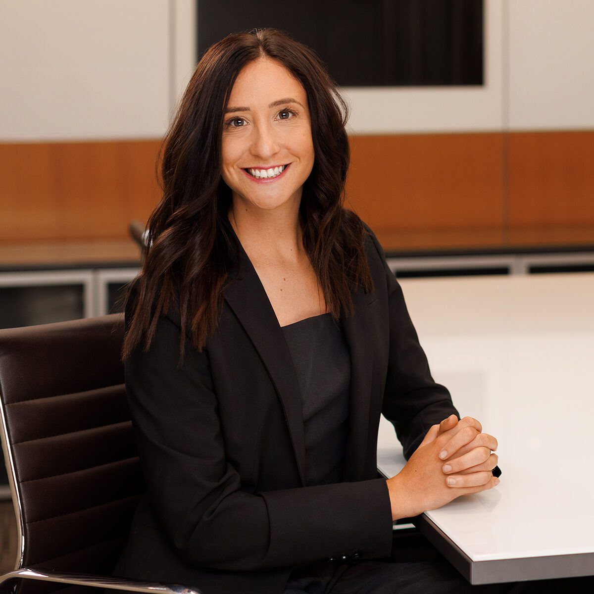 Remy Ventura professional headshot. She's sitting at a table in Pihl Law offices in Kelowna, BC.